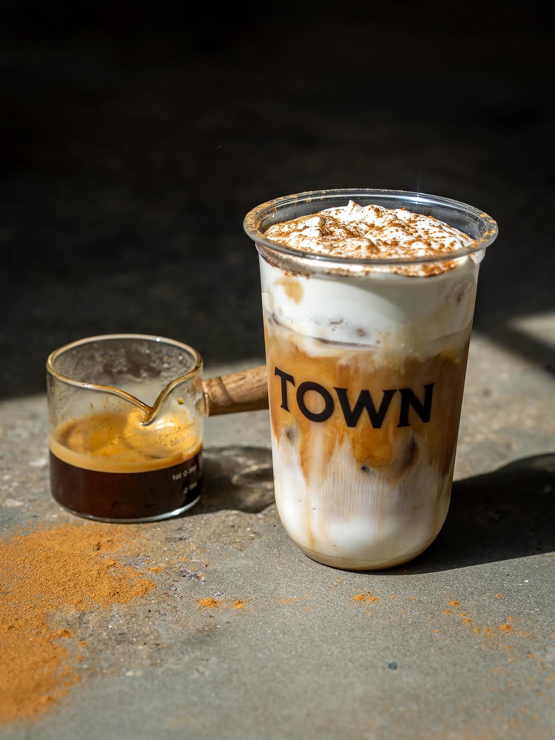 Cinnamon Roll Latte topped with foam and cinnamon beside an espresso shot